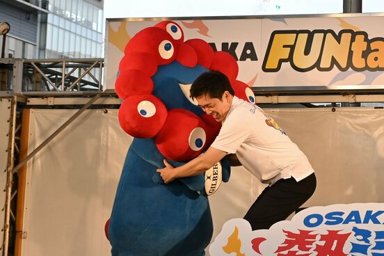 トライしようとするミャクミャクをディフェンスする吉村洋文知事