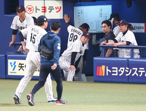 ９回、治療に向かう巨人・大勢(手前左)を心配そうに見つめる侍ジャパン・井端監督(中)
