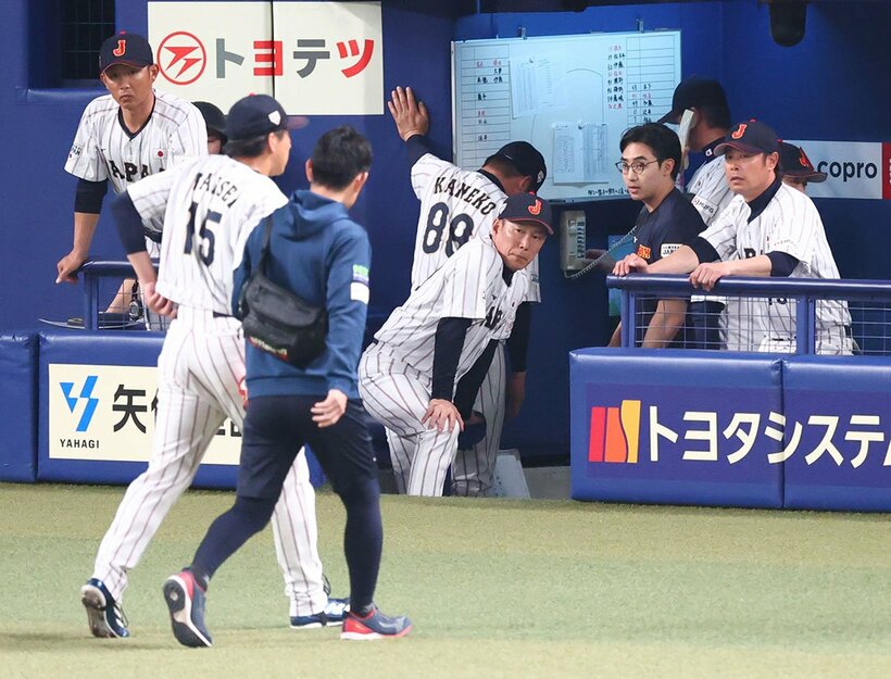 ９回、治療に向かう巨人・大勢(手前左)を心配そうに見つめる侍ジャパン・井端監督(中)