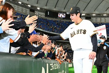 試合後、ファンとハイタッチする巨人・竹丸和幸