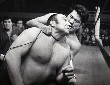 マイクコードでストンパー（手前）の首を絞める猪木（１９７１年２月、大田区体育館）