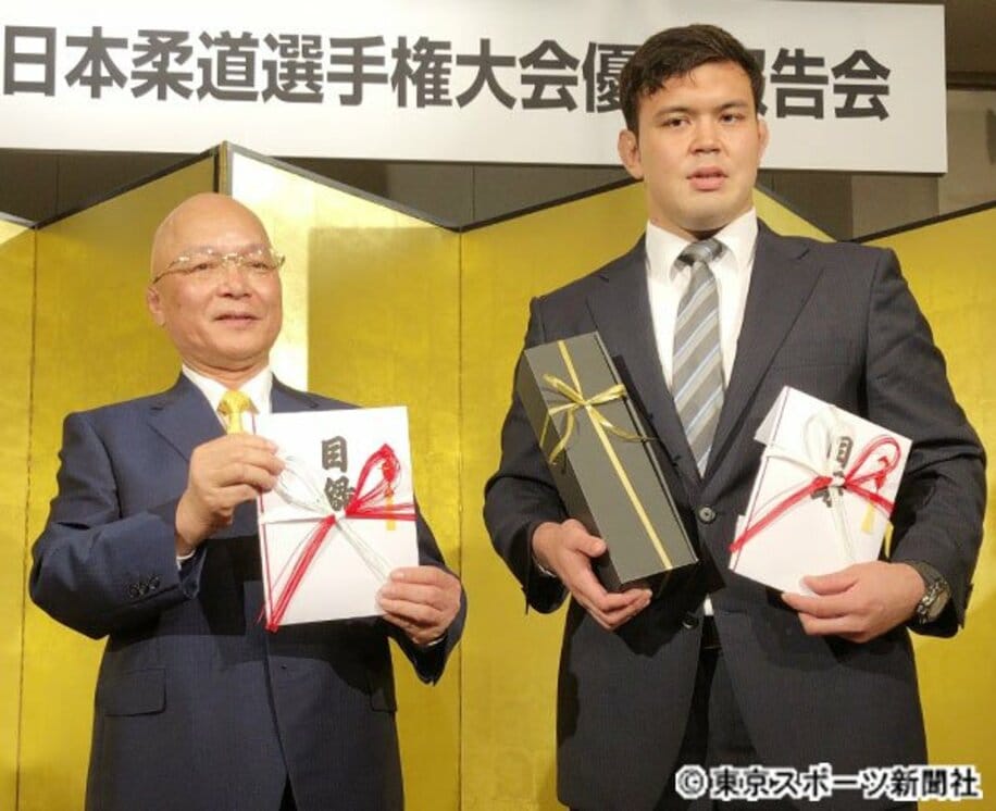  了徳寺健二理事長（左）から報奨金の目録を贈られたウルフアロン