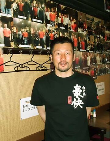  来店したプロ野球選手や有名人の写真が所狭しと並ぶ店内で笑顔を見せる藤田氏