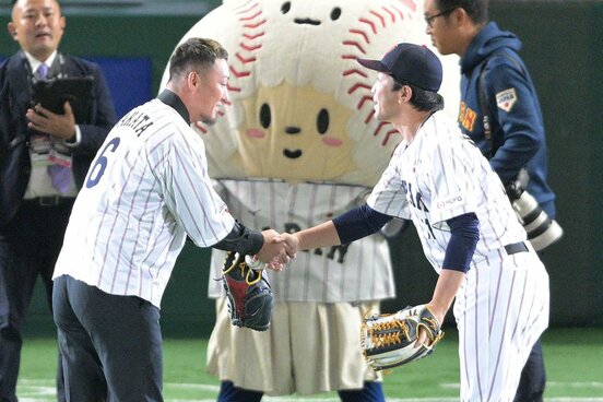 始球式で捕手を務めた侍ジャパン・松田宣浩コーチ(右)と握手を交わす中田翔氏