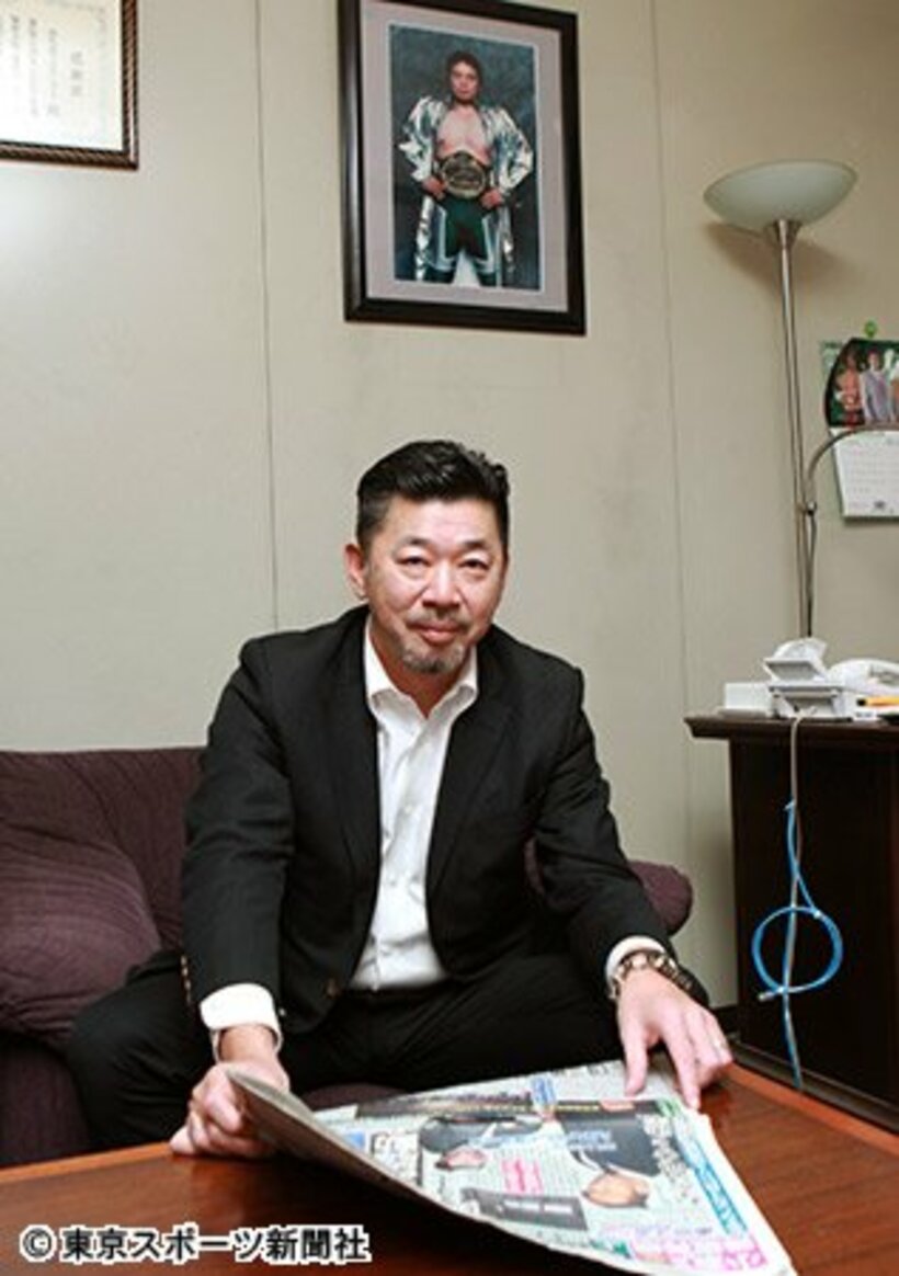 「ノア身売り」1面で報じた本紙を手にする内田氏。背後の壁にはノアの創設者・故三沢さんの写真が飾られていた