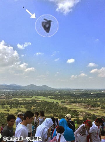白装束集団のはるか後方の上空に黒い物体が。拡大すると黒く奇妙な三角形のＵＦＯだった