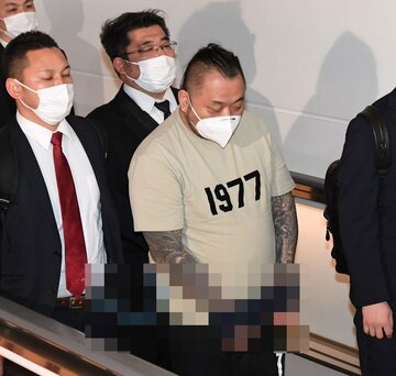 警視庁の捜査官に囲まれながら強制送還される小島智信容疑者
