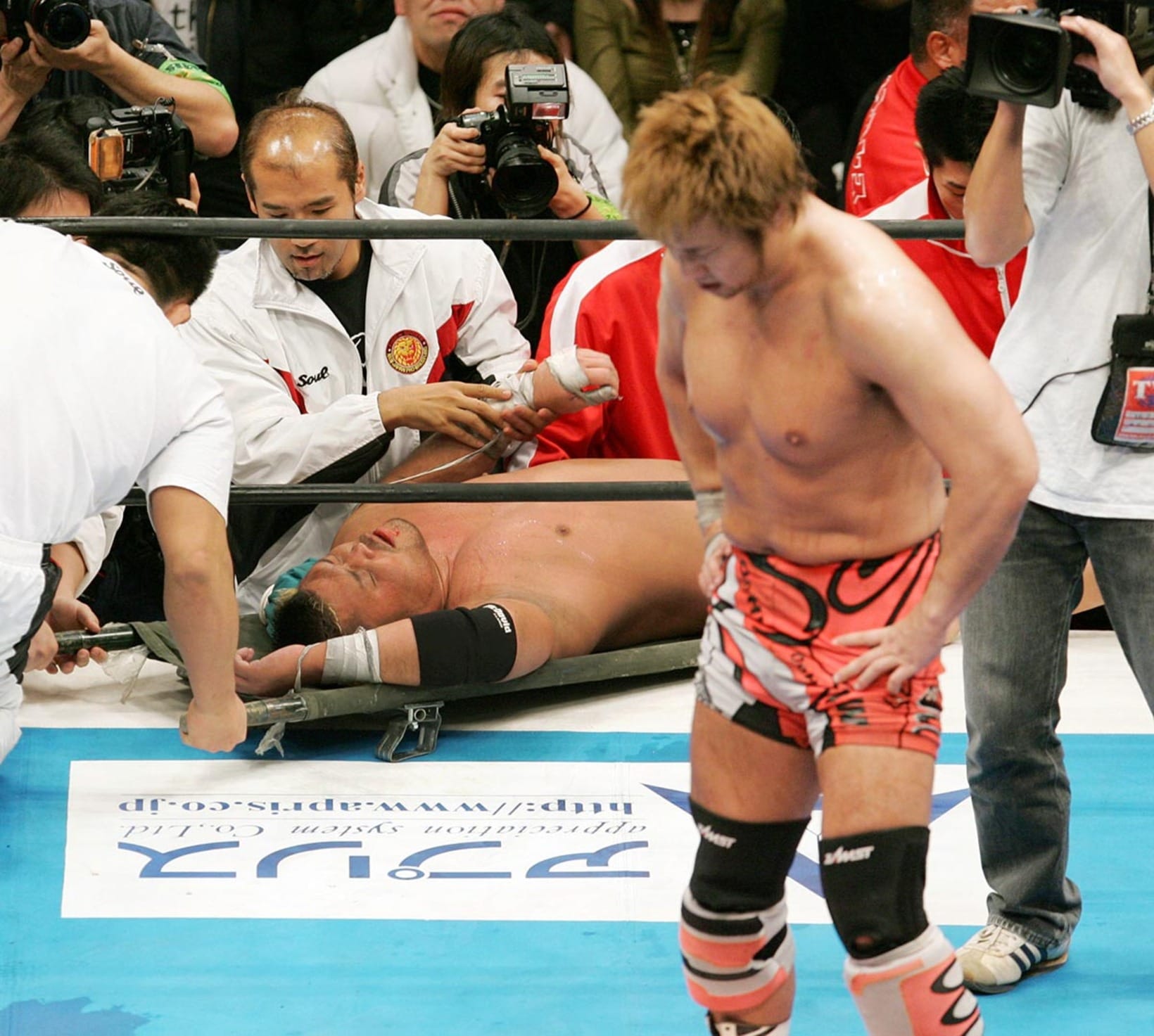 担架で運ばれる天山（奥）と顔を曇らせる小島（２００５年２月、両国国技館）