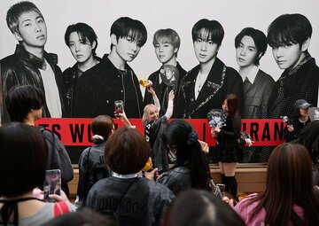 東京ドームに出されたＢＴＳの看板を前に、記念撮影するファンたち（ロイター）