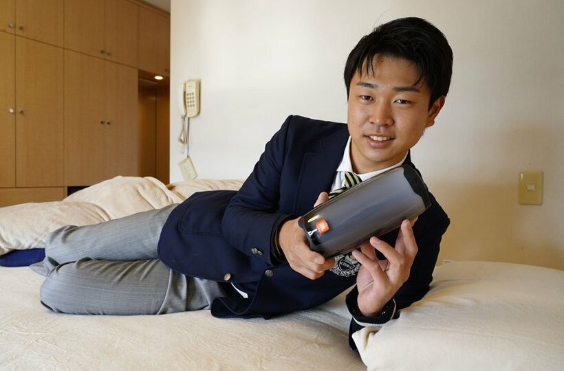  エアウィーヴに横たわり、大事なスピーカーを手にする中日・高橋宏斗（球団提供）